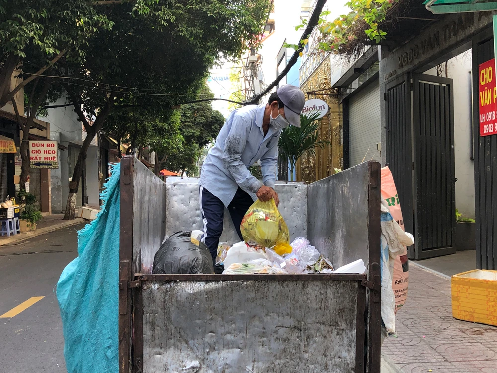 Công nhân thu gom rác vẫn cho tất cả rác thải vào chung xe ba gác để chở đến điểm tập kết