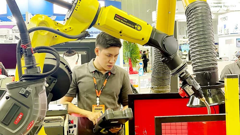 Nhân viên Công ty Makino (Khu Công nghệ cao TPHCM) điều khiển robot hàn điện, tạo chi tiết cho máy công nghiệp. Ảnh: HOÀNG HÙNG