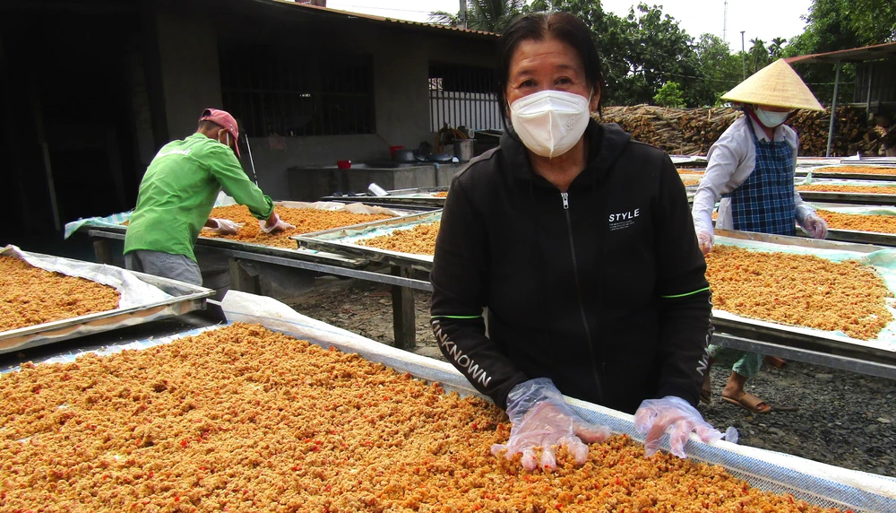 Bà Lê Thị Mỹ Vân cùng nhân công trộn muối tôm tại sân phơi. Ảnh: LÊ XUÂN