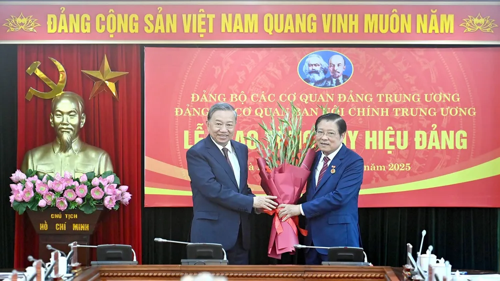 Tổng Bí thư Tô Lâm trao Huy hiệu 45 năm tuổi Đảng và tặng hoa chúc mừng đồng chí Phan Đình Trạc. Ảnh: NHÂN DÂN image.jpg