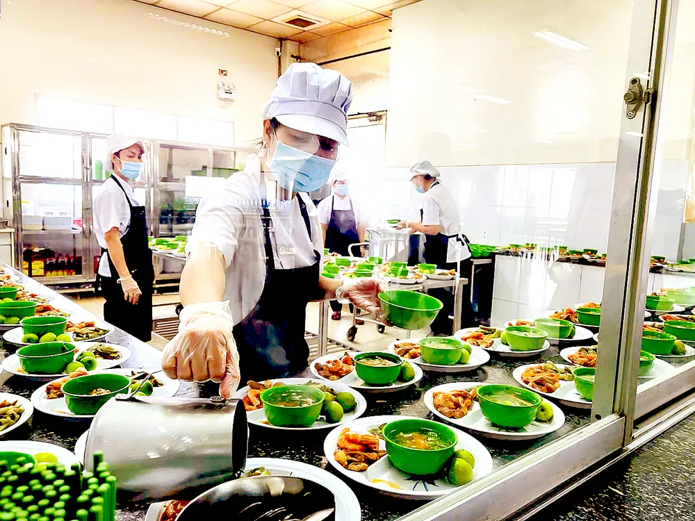 Chuẩn bị các suất ăn trưa tại một bếp ăn tập thể ở TPHCM. Ảnh: MINH KHUÊ R4d.jpg
