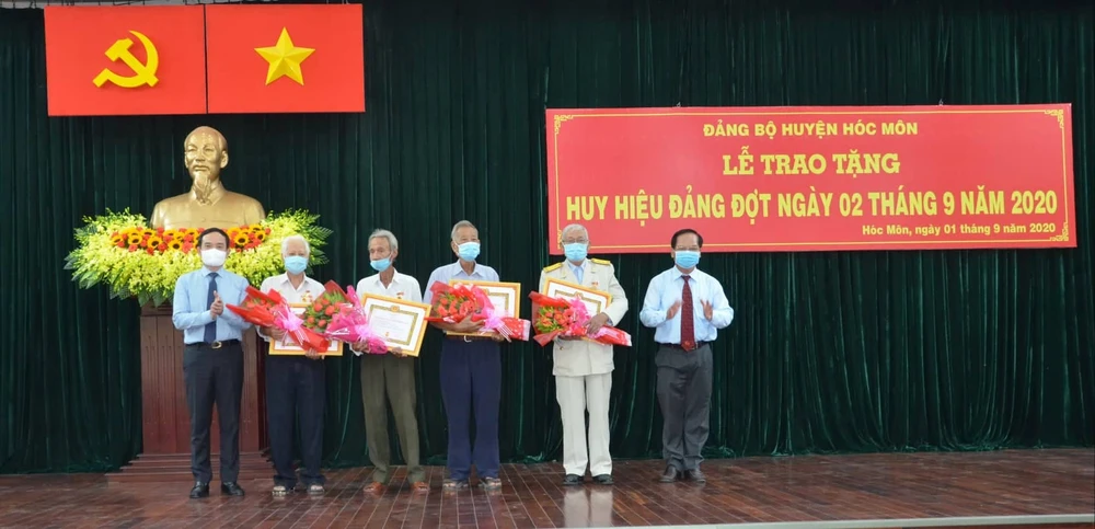 Đồng chí Trần Lưu Quang (bìa trái) tặng hoa chúc mừng các đảng viên 60 năm, 55 tuổi Đảng