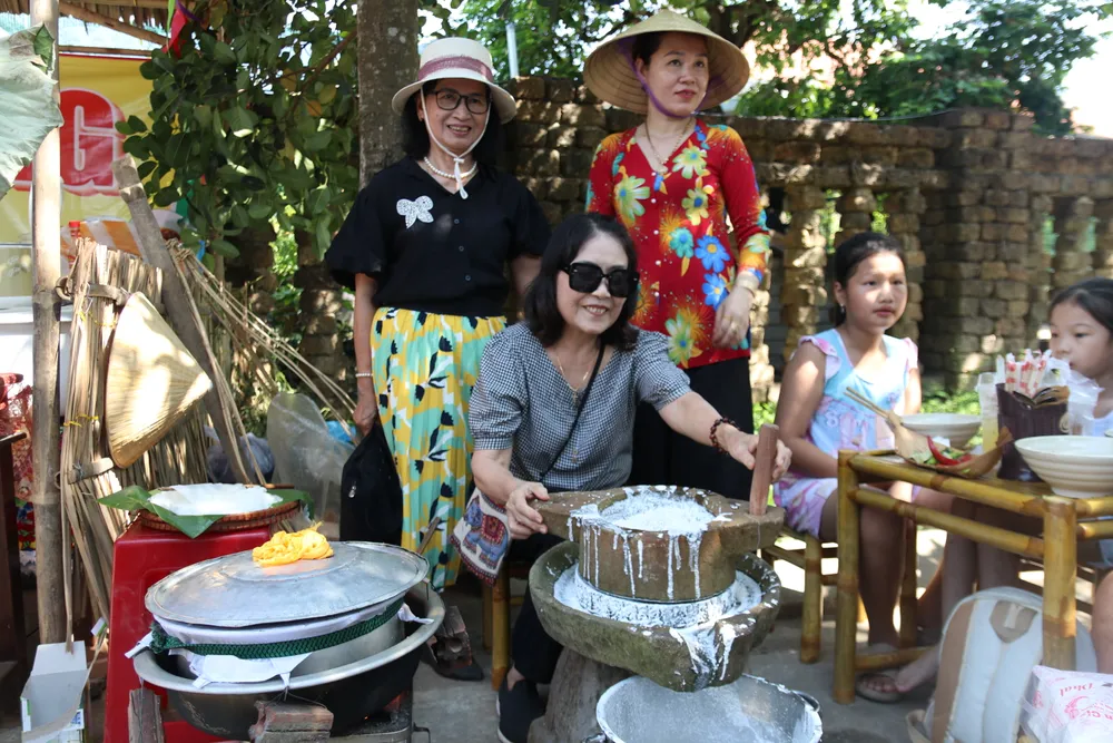 Du khách trải nghiệm xay bột để tạo ra lá Mỳ Quảng. Ảnh: NGUYỄN CƯỜNG 7-6-my-quang-1.JPG
