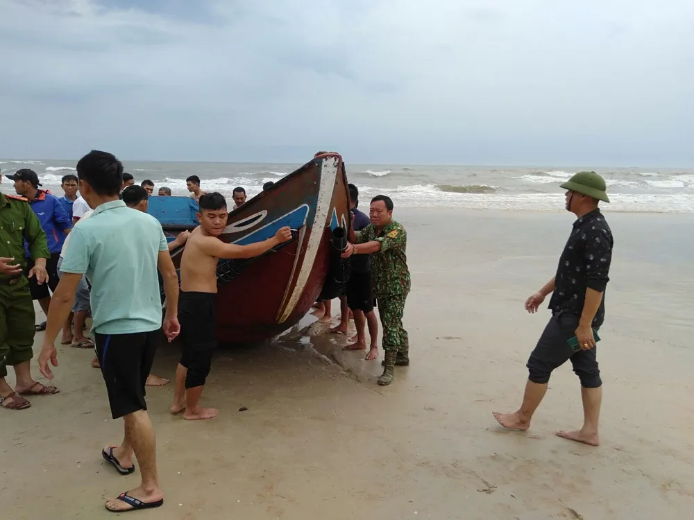 Lực lượng chức năng cùng người dân kéo thuyền bị chìm trên bờ Lực lượng chức năng cùng người dân kéo thuyền bị chìm trên bờ