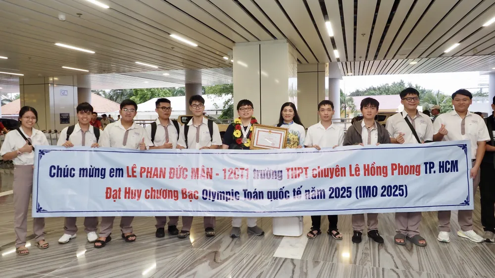 Ban Giám hiệu cùng học sinh Trường THPT chuyên Lê Hồng Phong chào đón Lê Phan Đức Mân ngay khi về đến sân bay Tân Sơn Nhất. Ảnh: HOÀNG HÙNG IMG_4831.jpeg