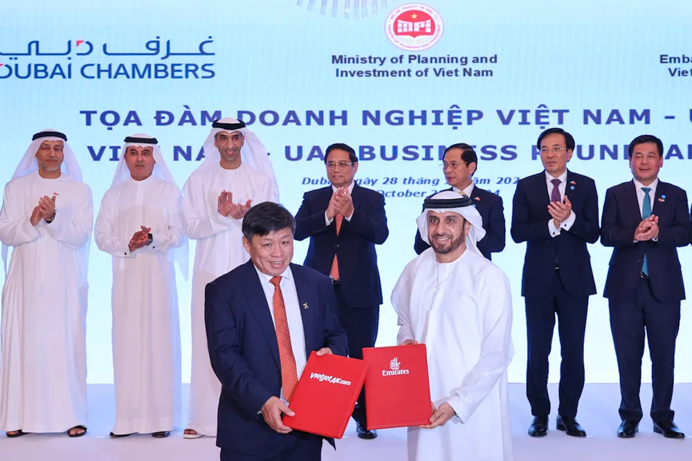 Đại diện lãnh đạo Vietjet (trái) và Emirates (phải) trao thỏa thuận hợp tác mở rộng kết nối quốc tế trước sự chứng kiến của Thủ tướng Phạm Minh Chính (giữa) tại Dubai, UAE Photo 2.jpg
