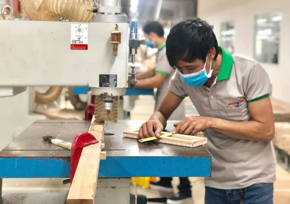 Công nhân Công ty nội thất gỗ Mê Kông (TP Tân Uyên, tỉnh Bình Dương) trong dây chuyền sản xuất. Ảnh: XUÂN TRUNG U5b.jpg