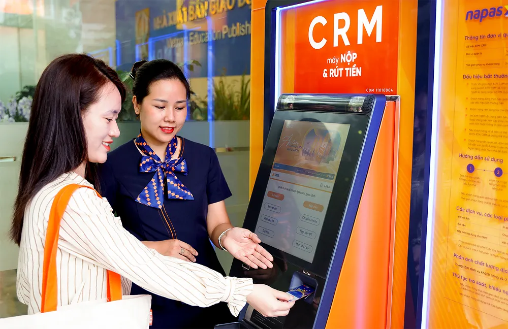 Giao dịch viên SHB hướng dẫn khách hàng sử dụng máy CRM Nhân viên SHB hướng dẫn khách hàng sử dụng máy CRM.png