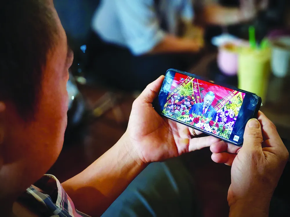 2025~2030年任期のホーチミン市党大会の厳粛な開会式を人々がスマートフォンでライブ視聴している。写真:タイ・フオン O5a.jpg