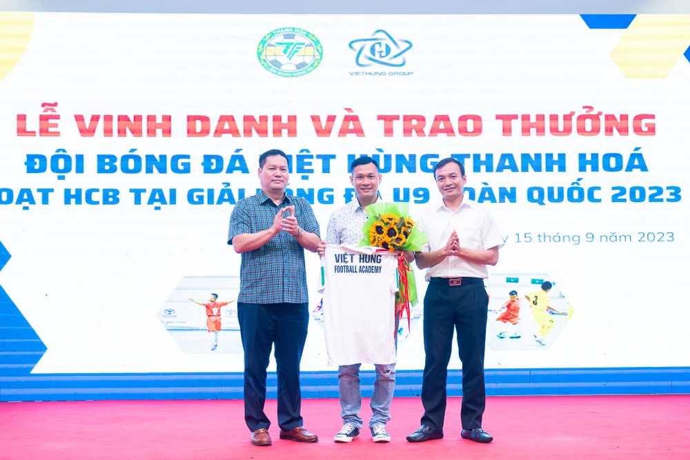 Ông Phạm Nguyên Hồng, Giám đốc Sở Văn Hóa, Thể Thao và Du Lịch Thanh Hóa (trái) và ông Lưu Văn Mạnh, Giám đốc Công ty CP Phát Triển Việt Hùng tặng hoa ra mắt tân Giám đốc Kỹ thuật Nguyễn Bảo Quân. 