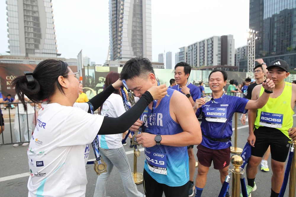 Các tình nguyện viên trao huy chương cho các runner khi về đích. ẢNH: DŨNG PHƯƠNG 