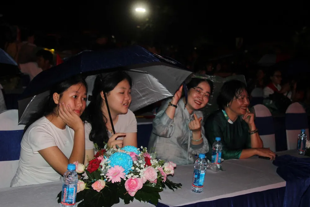 Khán giả đội mưa theo dõi chương trình tại điểm cầu phường Bình Dương. ẢNH: XUÂN TRUNG IMG_9404.JPG