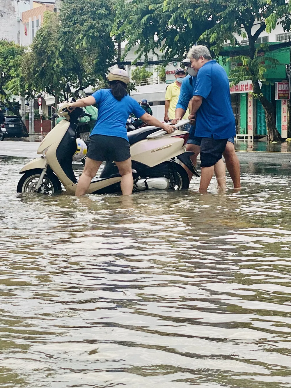 Người dân hỗ trợ một phụ nữ điều khiển xe máy gặp khó khăn