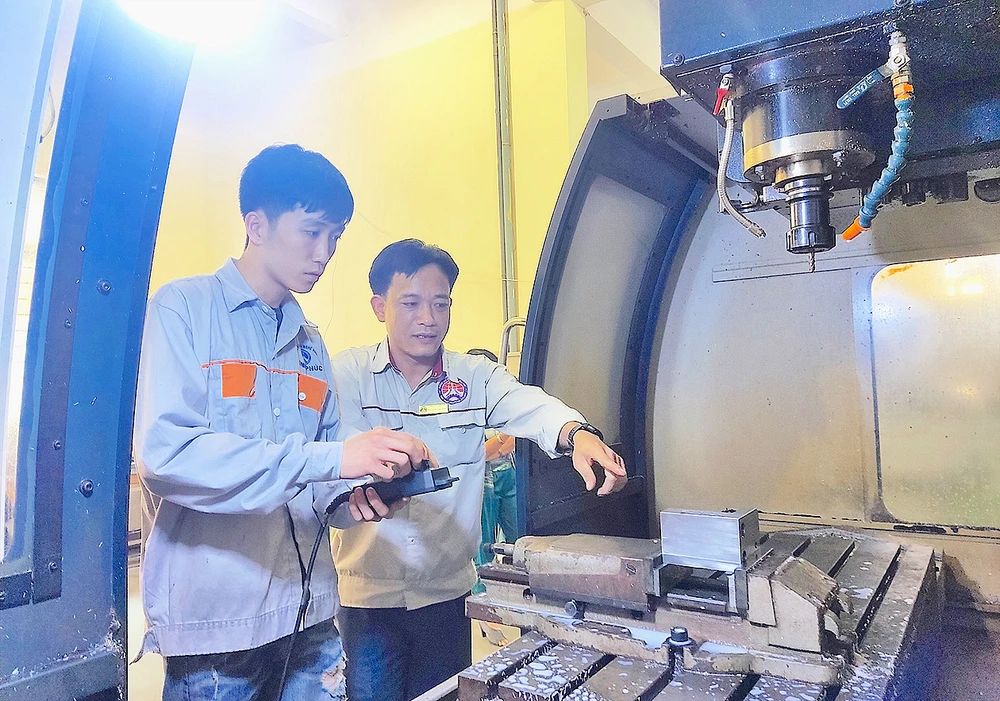 ThS Lê Thành Chung (phải), Trưởng khoa Cơ khí chế tạo, Trường Cao đẳng nghề Vĩnh Phúc, hướng dẫn sinh viên thực hành trên máy CNC