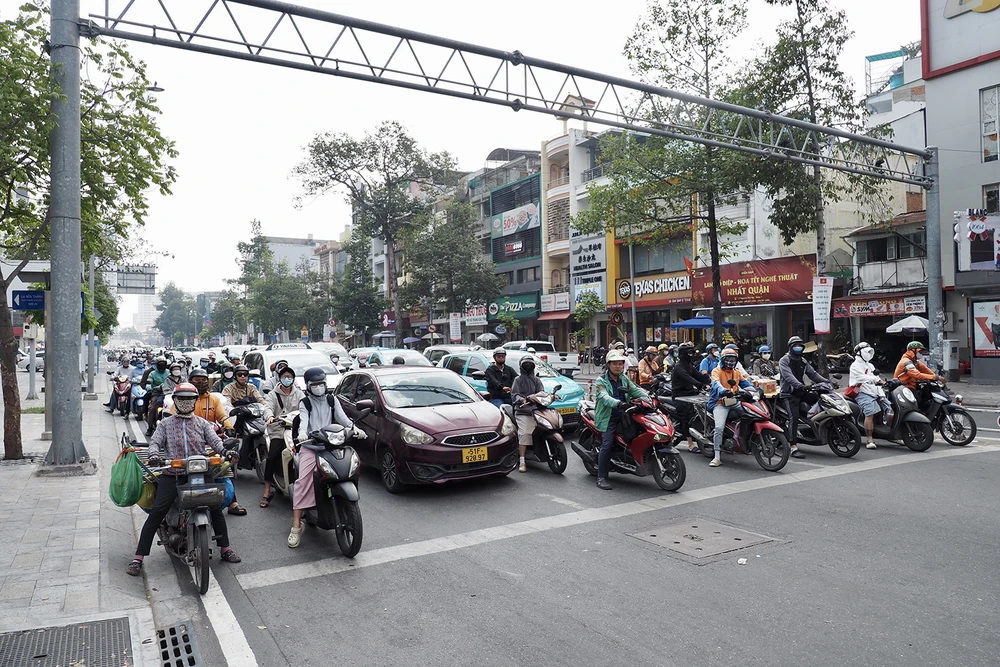 Người tham gia giao thông dừng xe đúng vạch kẻ khi đèn đỏ tại giao lộ Nguyễn Thái Học - Trần Hưng Đạo, quận 1, trưa 8-1. Ảnh: HOÀNG HÙNG