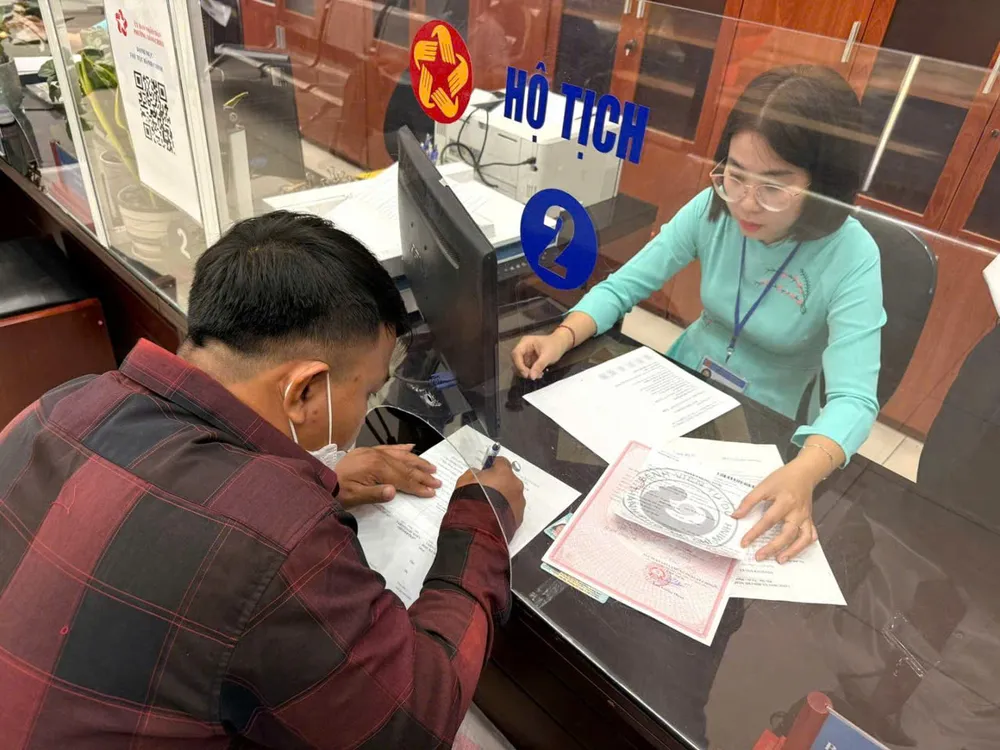 Ông Võ Nhất Tường được công chức Bộ phận một cửa UBND quận 4 hướng dẫn làm khai sinh cho con. Ảnh: THÁI PHƯƠNG 1.jpg