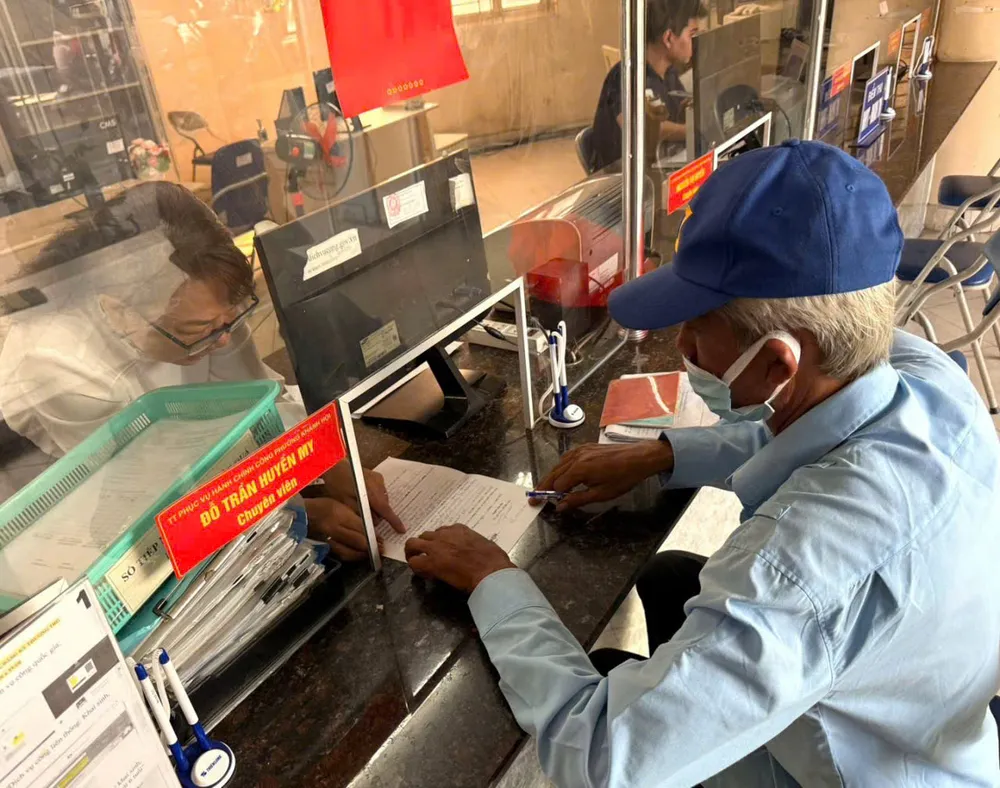 Ông Hồ Ngọc Huân được cán bộ phường 8, quận 4 hướng dẫn làm hồ sơ. Ảnh: THÁI PHƯƠNG 3.jpg