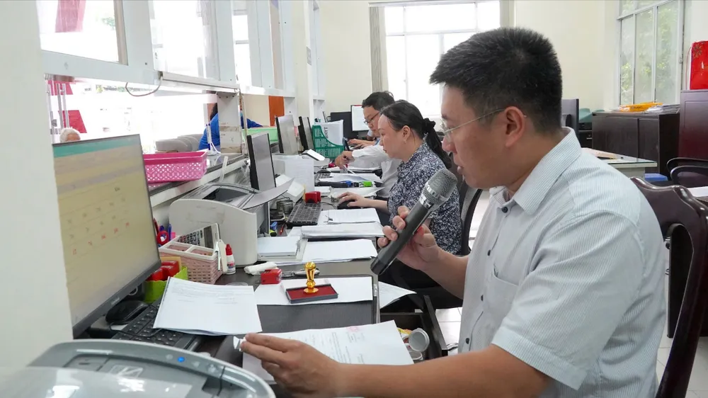Cán bộ không chuyên trách phường Tân Thuận tiếp nhận thủ tục hành chính của người dân tại Trung tâm Phục vụ hành chính công phường. Ảnh: PHƯƠNG UYÊN