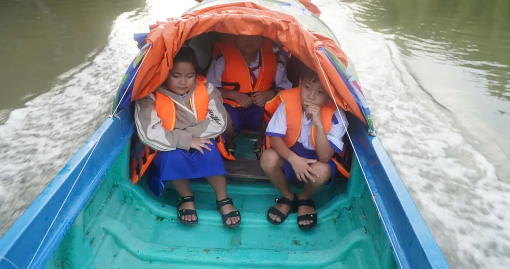 សិស្សសាលាបឋមសិក្សា Dat Mui 1 (ឃុំ Dat Mui ខេត្ត Ca Mau) ត្រូវបានឪពុកម្តាយនាំទៅសាលារៀនក្នុងសំប៉ាន។ រូបថត៖ តាន់ ថៃ z6978318411117_0f20f7f1f4e84c2fc159d5fa1031371d.jpg