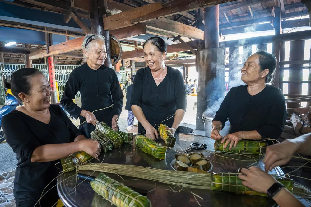 Пані Ле Тхі Кіем (друга зліва) — онука пана Ле Ван Муу в четвертому поколінні, разом з мешканцями та людьми загорнула бань тет, щоб пригостити гостей звідусіль. Фото: HOAI AN nha lon - long son 15.jpg