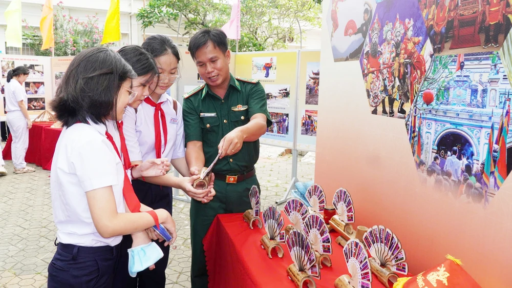 Chiến sĩ biên phòng giới thiệu cho các em học về di sản nghệ thuật Bài Chòi. Ảnh: HOÀNG NGỌC z6592689167426_06d06e185629b170fd8559e13397980e.jpg