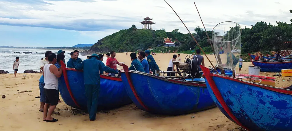 Lực lượng chức năng hỗ trợ ngư dân Phù Mỹ Bắc đưa ghe thuyền lên bờ tránh bão ngày 27-9. Ảnh: XUÂN HUYÊN z7062806515571_09daa7bce74bf184cc6c8d2146567467.jpg