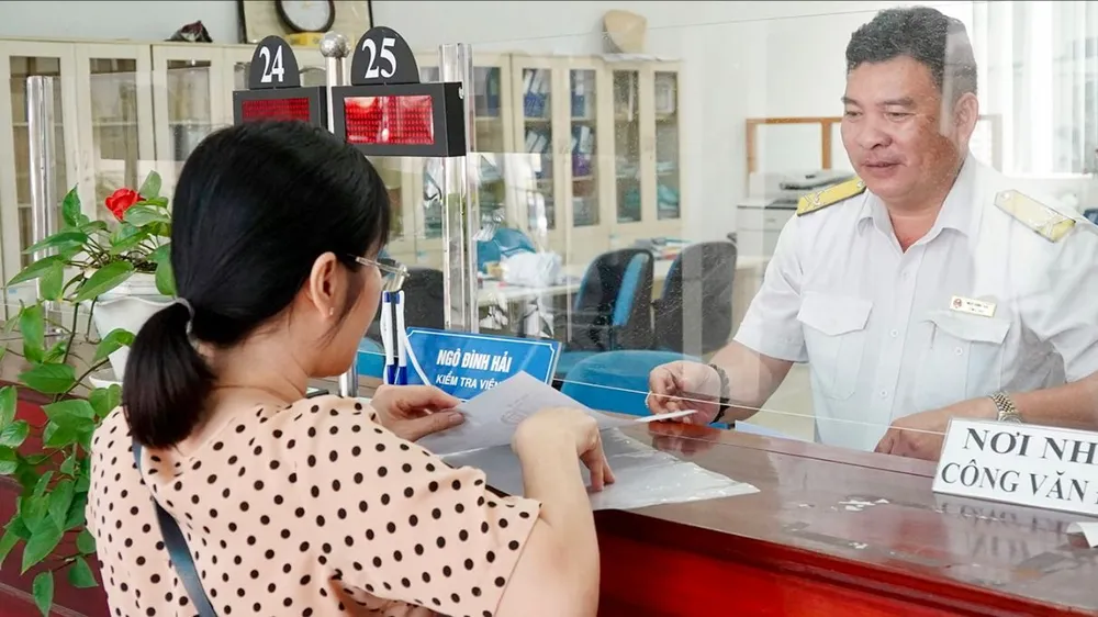 Cán bộ thuế TPHCM hướng dẫn người nộp thuế thực hiện thủ tục. Ảnh: HOÀNG HÙNG R5b.jpg