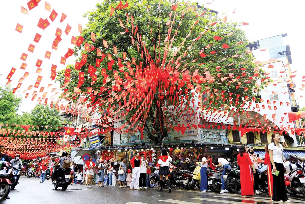People in Hang Ma Street, Hanoi, hang flags to decorate the streets to celebrate the 80th anniversary of the August Revolution and National Day, September 2. Photo: HA NGUYEN S2b.jpg