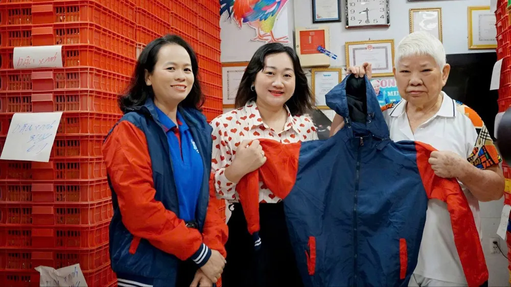Phó Tổng Biên tập Báo SGGP Bùi Thị Hồng Sương tiếp nhận áo ấm do bà Nguyễn Thị Dậu, chủ cơ sở Như Lan, trao tặng. Ảnh: VIỆT NGA