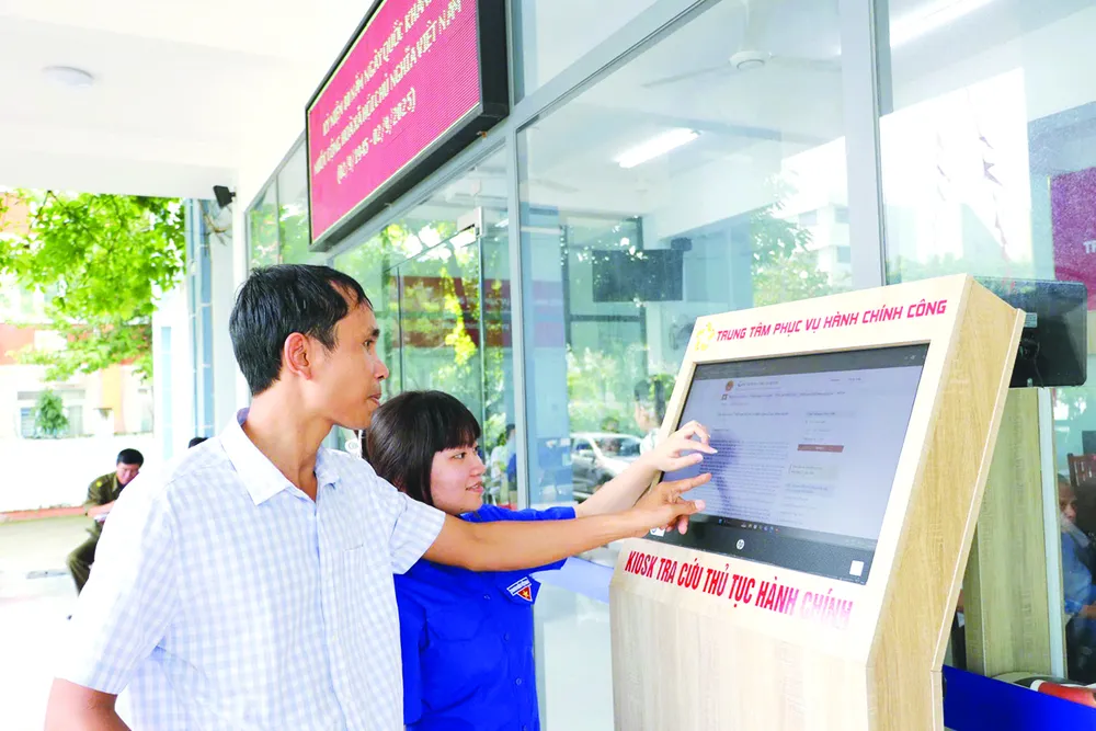 Thanh niên tình nguyện hỗ trợ người dân thực hiện thủ tục hành chính tại Trung tâm Phục vụ hành chính công phường An Phú Đông (TPHCM). Ảnh: NGÔ BÌNH P1c.jpg
