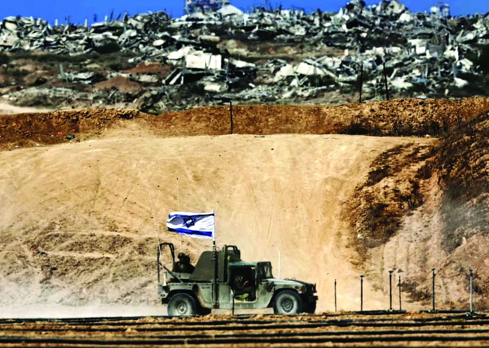 Xe quân sự của Israel chạy qua các tòa nhà bị phá hủy dọc biên giới với Dải Gaza. Ảnh: EPA H8d.jpg