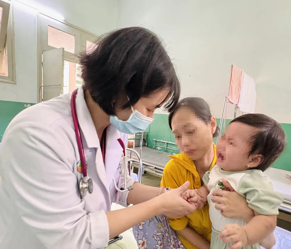 Bác sĩ Bệnh viện Nhi đồng 2 thăm khám cho bệnh nhi mắc tay chân miệng. Ảnh: THÀNH AN T7a.jpg