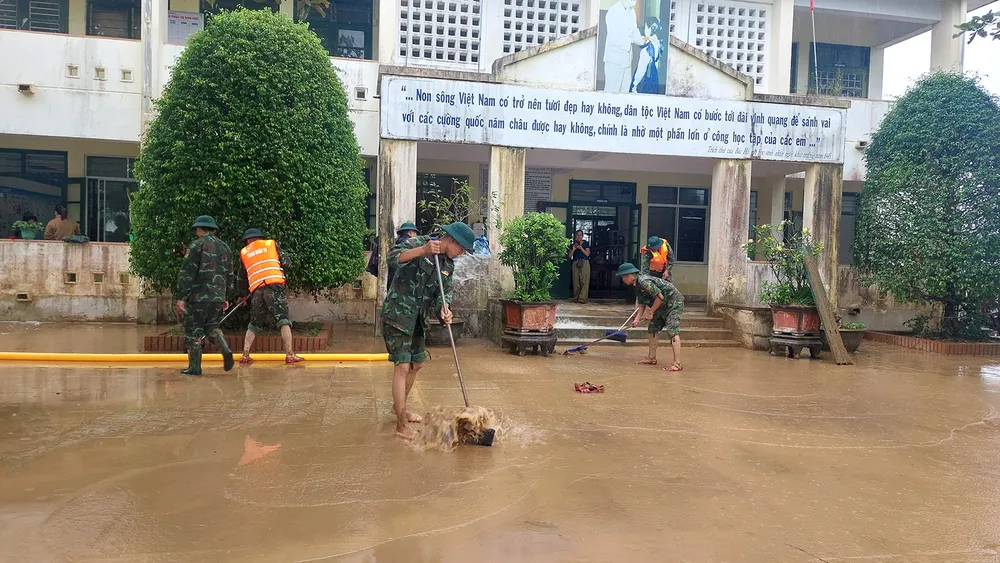 Cán bộ, chiến sĩ Trung đoàn 19 dọn lớp bùn non để lại khi lũ rút, giúp thầy trò Trường Tiểu học và THCS Cam Tuyền (Quảng Trị) đến trường trở lại