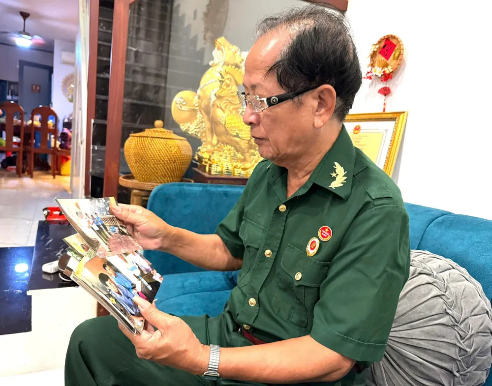Ông Vũ Đức Hân xem lại từng tấm hình của đồng đội và những ngày lặn lội rừng sâu tìm hài cốt đồng đội mình c8eddbdd58d2d18c88c3.jpg