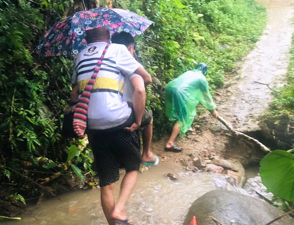 Người dân vùng nguy cơ sạt lở được hỗ trợ đưa đến nơi an toàn. Ảnh: VI OANH NA-vuotnuocchayxiet1.jpg