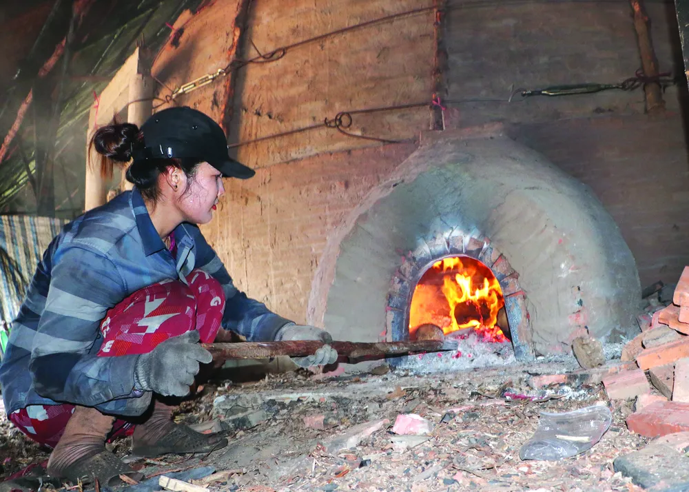 Nachdem die Arbeiter den Ofen mit Mangrovenholz gefüllt hatten, versiegelten sie ihn und zündeten die Kohlengrube an. Foto: TAN THAI CN1g.jpg
