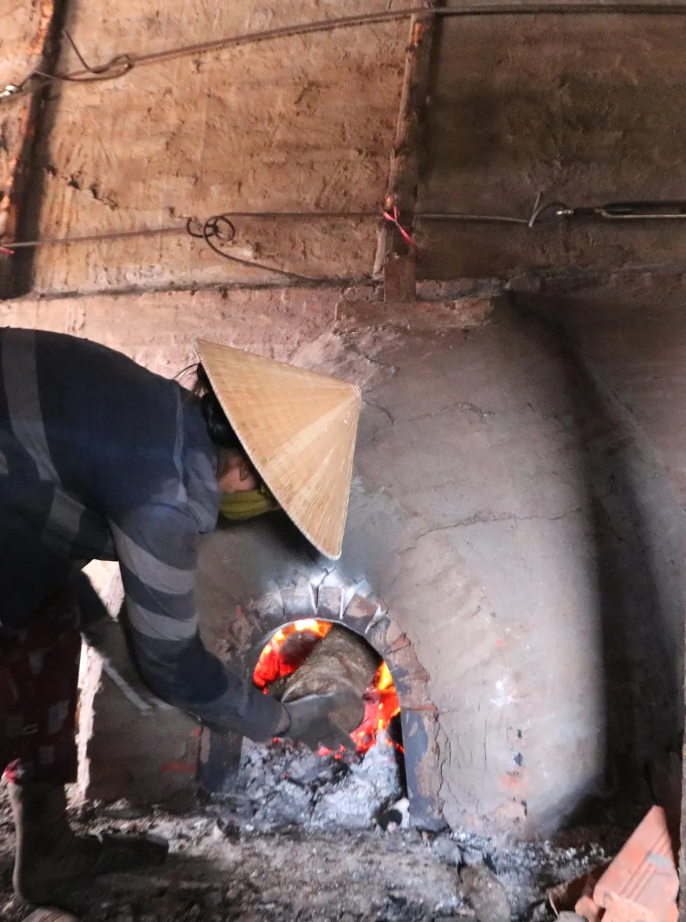 Nachdem die Arbeiter den Ofen mit Mangrovenbrennholz gefüllt hatten, versiegelten sie ihn und entzündeten ein Feuer in der Holzkohlegrube. PSA Anh14-Ham Than 57.jpg