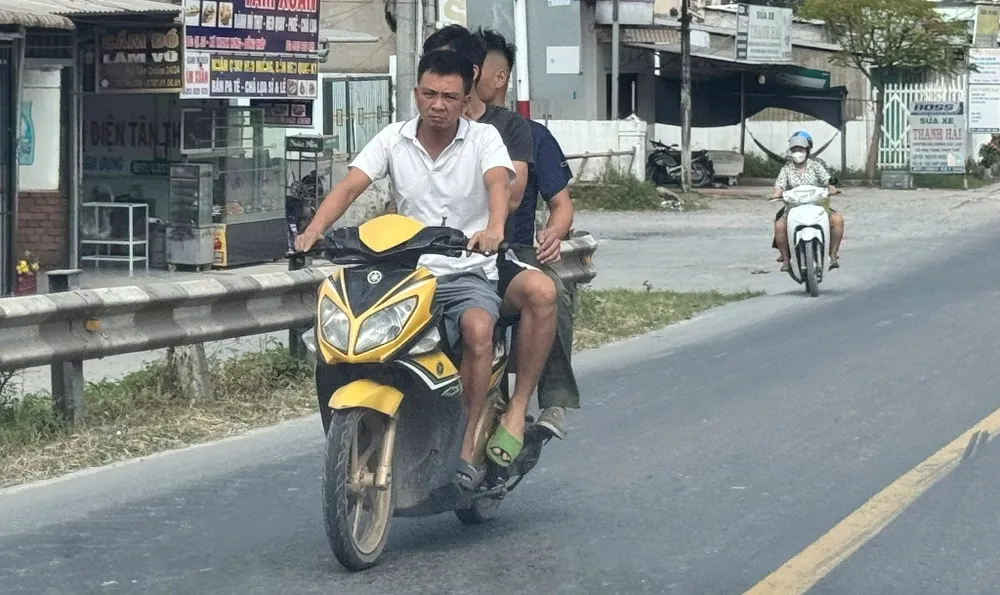 Xe mô tô “cõng” 3 người nhưng không ai đội mũ bảo hiểm đang lưu trên Quốc lộ 30, đoạn thuộc địa phận xã Thanh Hưng, tỉnh Đồng Tháp - Ảnh: Bùi Nguyên ảnh 2.jpg