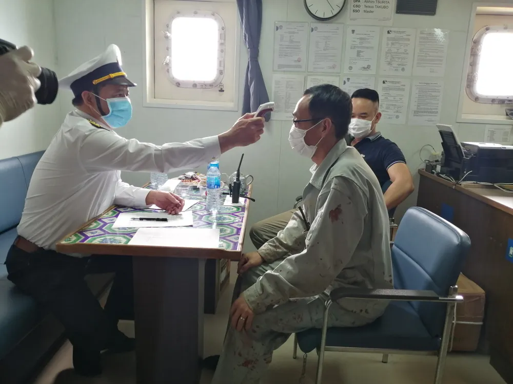 Đo thân nhiệt thuyền viên trước khi đưa lên bờ cách ly