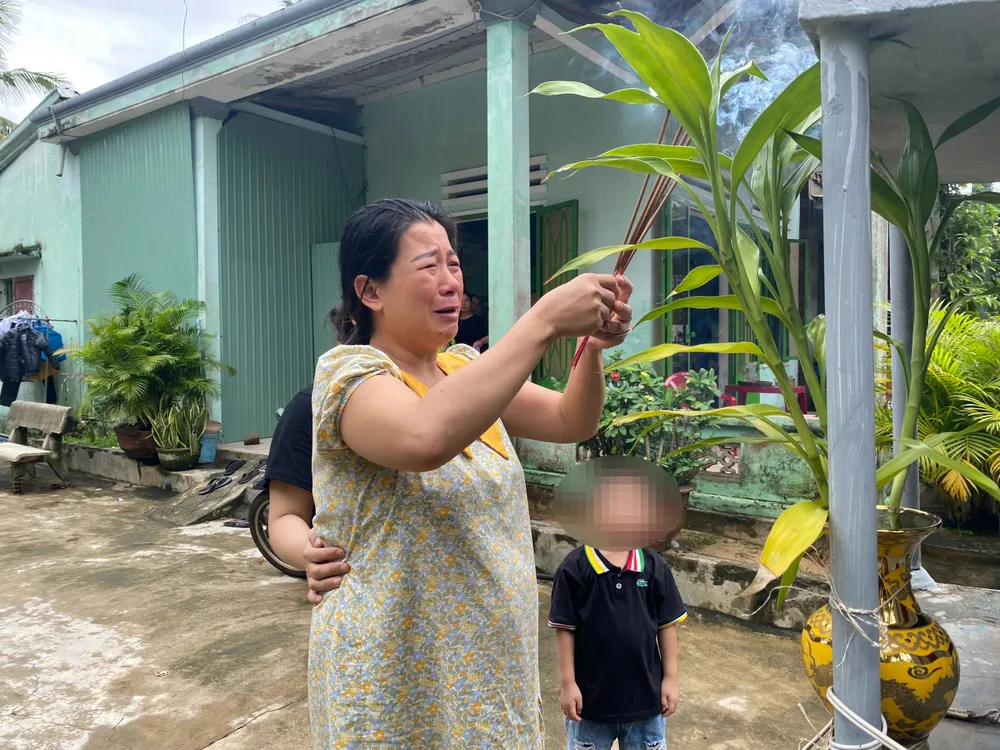 Chị Phạm Thị Liên thắp nhang cầu nguyện cho chồng. Ảnh: PHẠM NGA