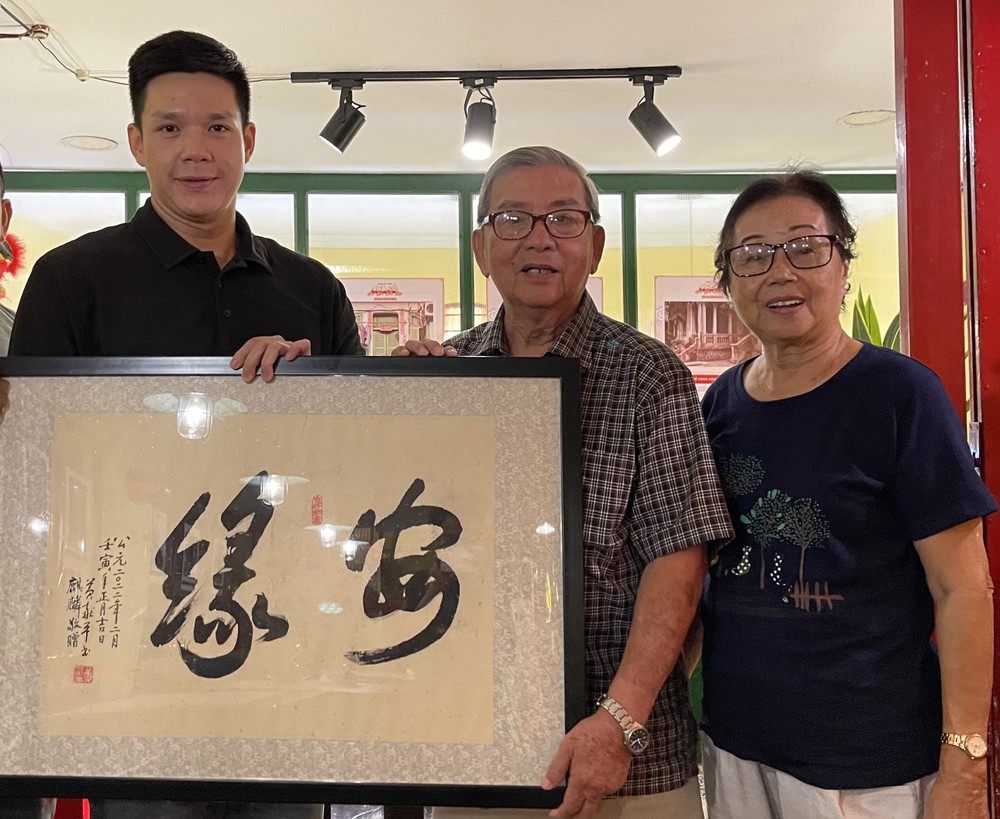 華人書畫家黃獻平(中)給鄧國長(左)贈送墨寶。
