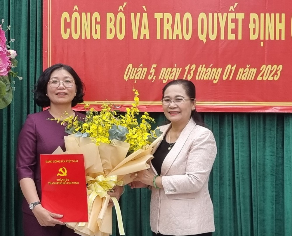 市委副书记、市人民议会主席阮氏丽(右)向黄玉女芳红同志颁发第五郡郡委书记《决定》。