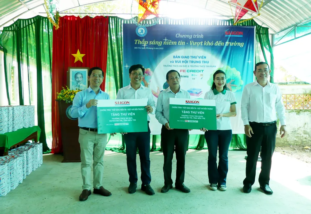 Đại diện các đơn vị trao bảng tượng trưng tài trợ 2 thư viện của Trường THCS An Đức và Trường THCS Tân Xuân. Ảnh: VIỆT NGA