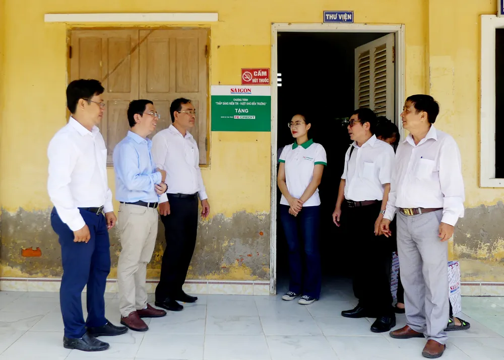 Ban tổ chức cùng gỡ bảng trao tặng thư viện Trường THCS An Đức. Ảnh: VIỆT NGA