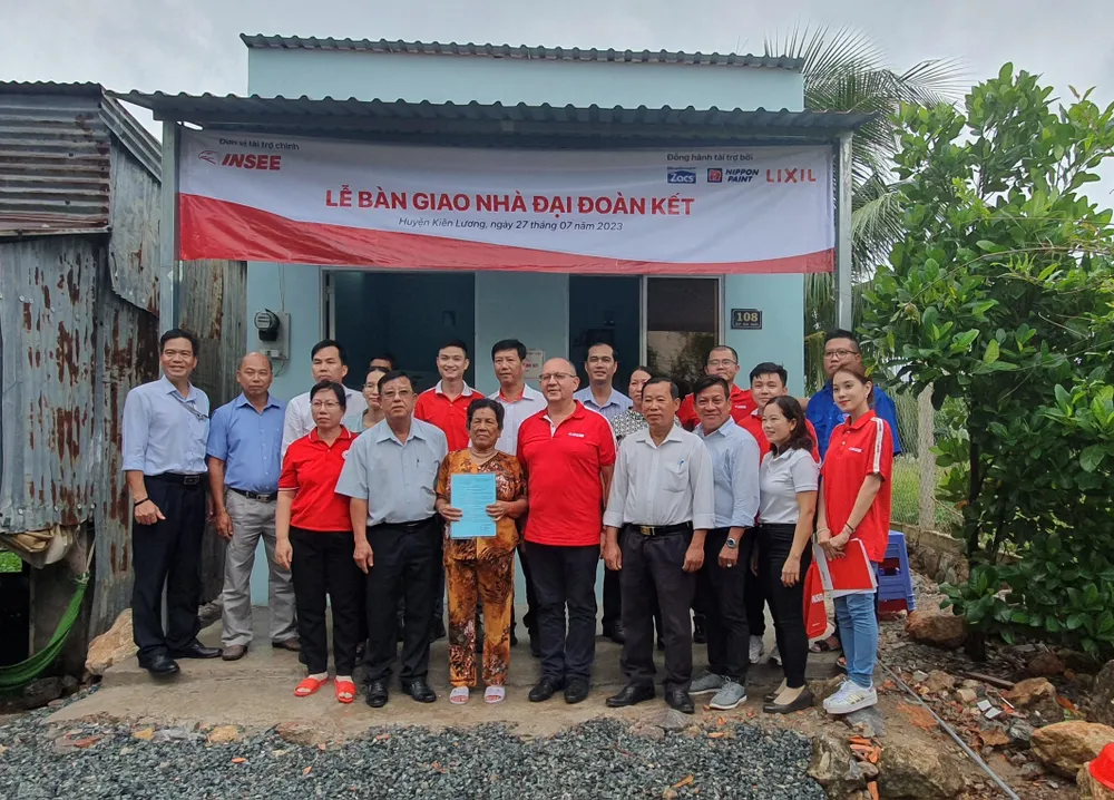 Cụ Trần Thị Lý (giữa) vui mừng chụp ảnh lưu niệm cùng đại diện xi măng INSEE và chính quyền địa phương. Ảnh: Q.B