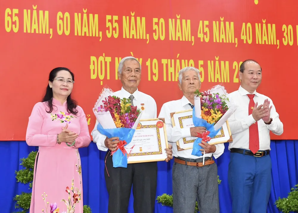Chủ tịch HĐND TPHCM Nguyễn Thị Lệ và Bí thư Huyện ủy huyện Củ Chi Nguyễn Quyết Thắng trao tặng Huy hiệu 65 năm tuổi Đảng cho các đảng viên. Ảnh: VIỆT DŨNG