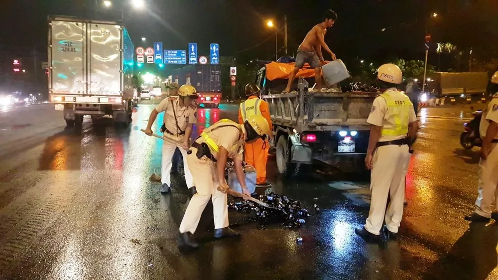 Cảnh sát giao thông hỗ trợ công nhân vệ sinh thu dọn vỏ chai đổ trên đường ảnh 3