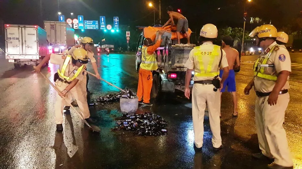 Cảnh sát giao thông hỗ trợ công nhân vệ sinh thu dọn vỏ chai đổ trên đường ảnh 2