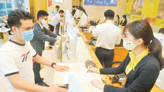 Customers do transactions at a bank in Ho Chi Minh City. (Photo: SGGP)