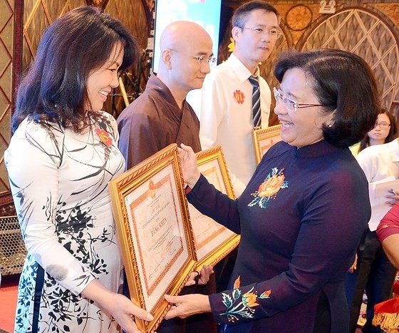 Ms.Than Thi Thu, Head of the Department of Propaganda & Education of HCMC Party Committee (R ) offers certificates of merit to individuals and organizations at the ceremony. (Photo: Sggp)